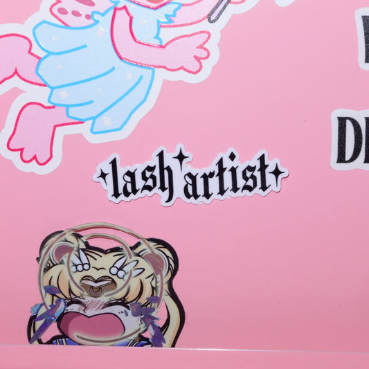 Sticker with 'lash artist' text and cartoon character on a pink background